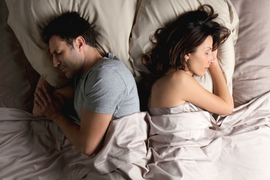 una coppia dorme schena contro schiena, con il viso rivolto all'esterno del letto