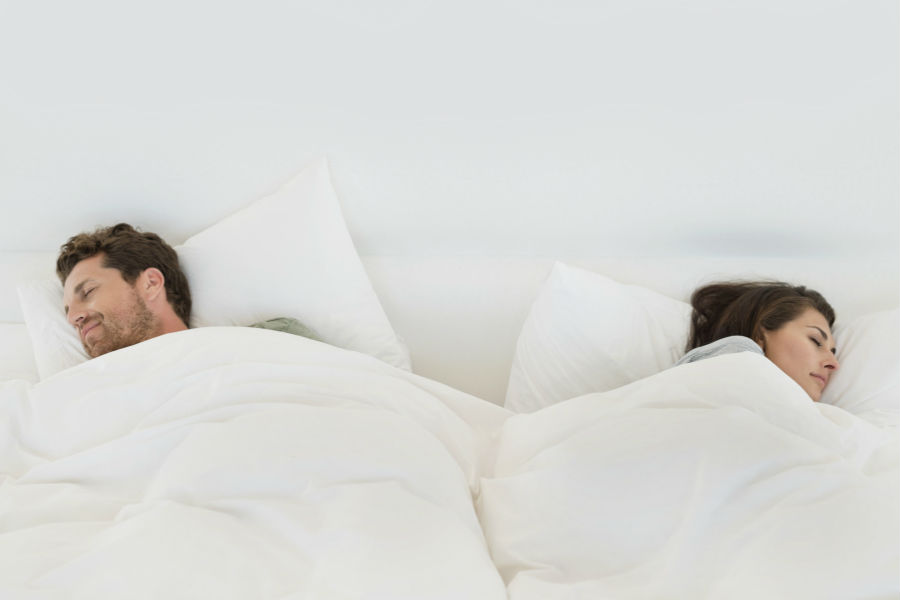 una coppia dorme agli estremi del letto, con i visi rivolti verso l'esterno